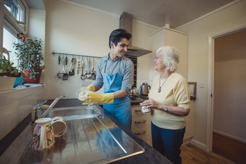 A professional caregiver helping a senior with light housekeeping to ensure a safe and tidy home environment