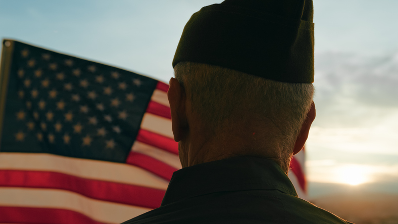 An elderly veteran silhouetted against the American flag, representing veteran in-home care