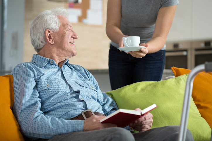 A man in respite care receives a fresh cup of coffee from a caregiver.