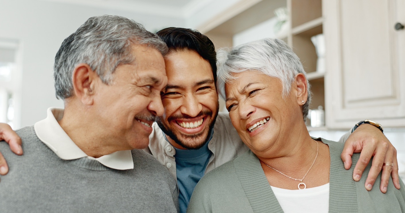 A man embracing his elderly parents - he is learning how to care for aging parents at home as their needs increase.