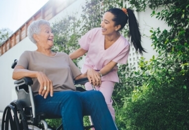 ComForCare Caregiver taking a client in a wheelchair outside in Waukesha County to enjoy the spring weather.