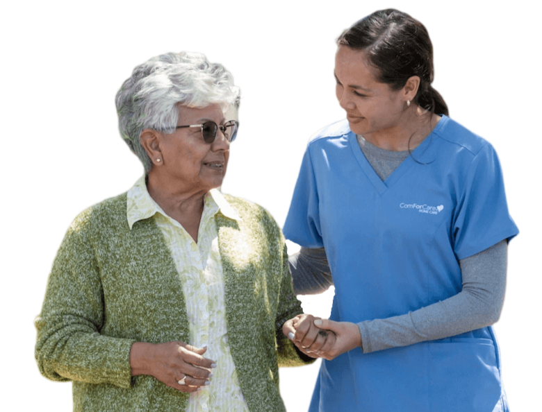 ComForCare Caregiver walking with a senior woman outside on a sunny day.