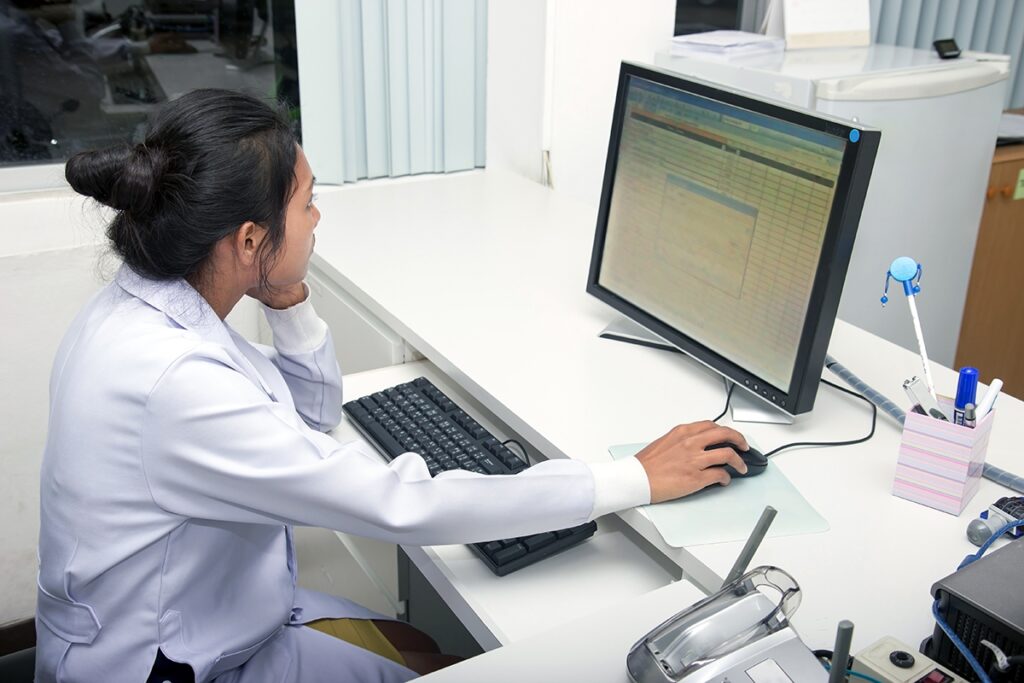 A physician reviewing records on a computer.