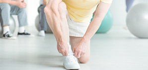 Someone bent down during an exercise class tying their shoe.