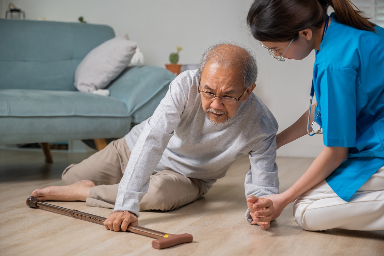 A caregiver helping an older gentleman off the floor after a fall.