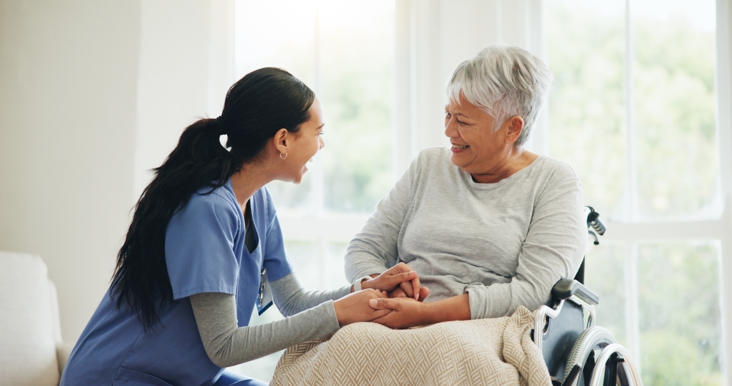 A caregiver talking to an older lady in a wheelchair.